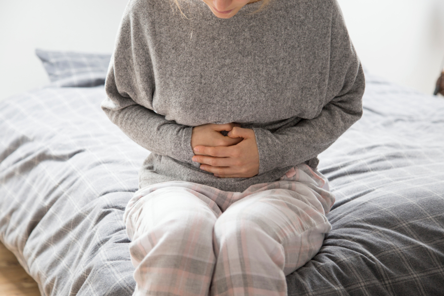 Collagen peptides benefits: a woman holding her stomach.