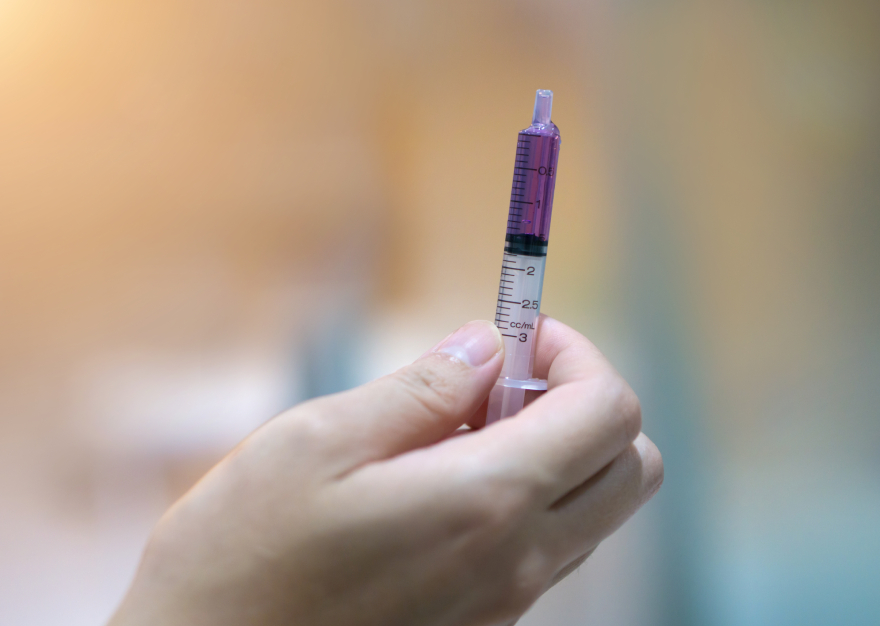 Mounjaro cost: a man holding a medicine-filled syringe.