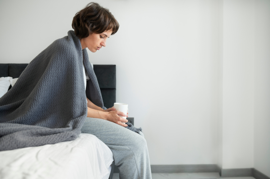 Ozempic alternatives: a woman feeling ill, sitting on a bed.