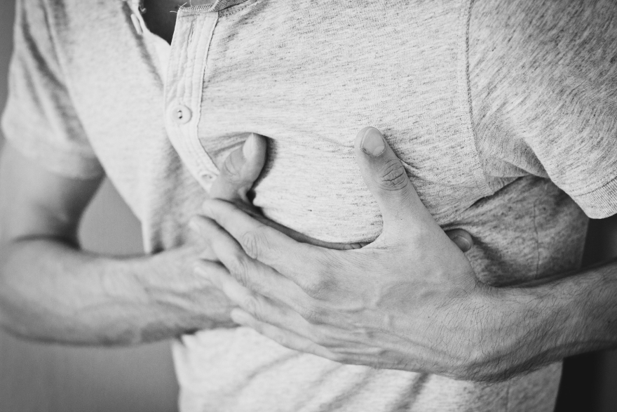 Sauna benefits: a man grabbing at his heart region.